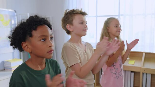 Group of diversity adorable student clapping hands at nursery school.