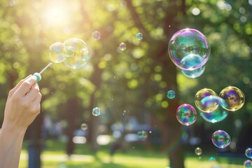 In a park, a man uses a bubble wand to blow colorful bubbles.