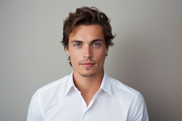 Fototapeta premium Portrait of a handsome young man in white shirt on grey background