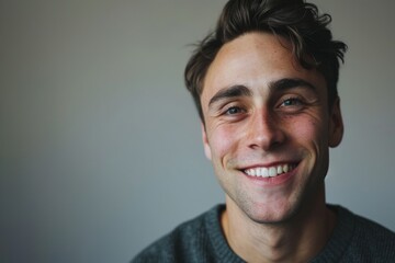 Fototapeta premium Portrait of a handsome young man in a grey sweater smiling.