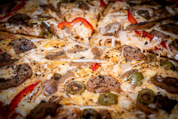 Close-up of a hand taking a slice of vegetarian pizza with onions, bell pepper, and vegetables on a wooden board.