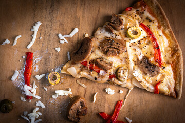 Close-up of a hand taking a slice of vegetarian pizza with onions, bell pepper, and vegetables on a wooden board.