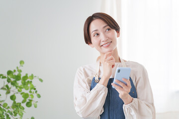 スマホで料理のレシピを調べる女性（キッチン・主婦）