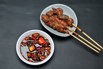 Satay with peanut sauce and soy sauce topped with chili slices and shallots is an Indonesian delight. Juicy grilled meat skewers paired with rich, spicy, and savory sauces.