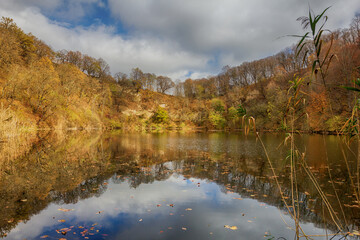 autumn day on a mountain lake of karst origin surrounded by a yellowing forest