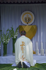 A priest kneels in front of the altar during the Corpus Christi procession
