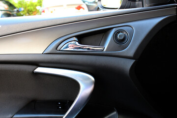 Fototapeta premium Drivers door trim. Door handle with windows controls. Car Door handle with rear view mirror adjustment.