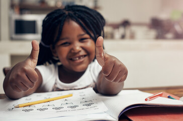 Black girl, portrait and thumbs up for education in home, homework and approval for learning. Female person, book and writing in kitchen for knowledge or information, satisfaction and development