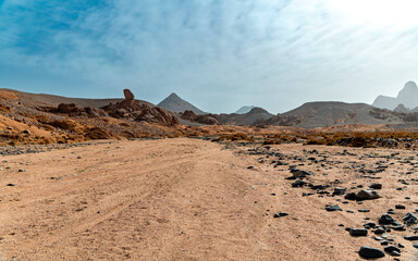 Sand road in the desert with mountains in the background