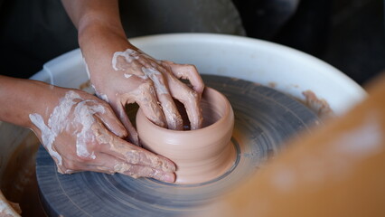 Hand making clay pottery at throwing wheel.