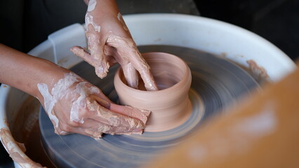 Hand making clay pottery at throwing wheel.