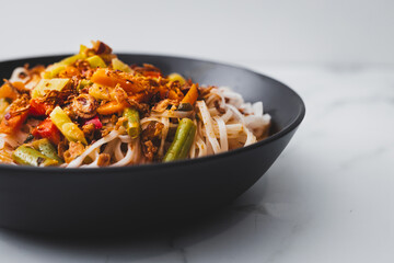 plant-based dan dan rice noodles soup with mixed vegetables and spicy sauce