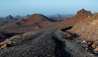  road on a rocky mountain with a red mountain in the background