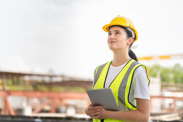 Fototapeta premium Cheerful female engineer with a digital tablet at the factory warehouse, Young beautiful woman foreman worker in the construction site
