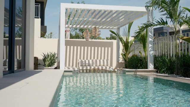 Small swimming pool with canopy and sofa in the backyard of a private villa in Dubai on a sunny day