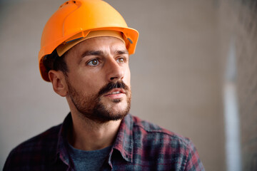 Portrait of manual worker at construction site looking away.