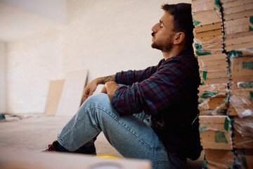 Tired worker relaxing with eyes closed at construction site.