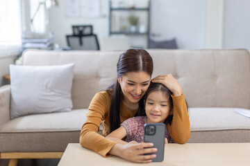 image of mother and daughter cuddling on the sofa using mobile phone waching movie online,