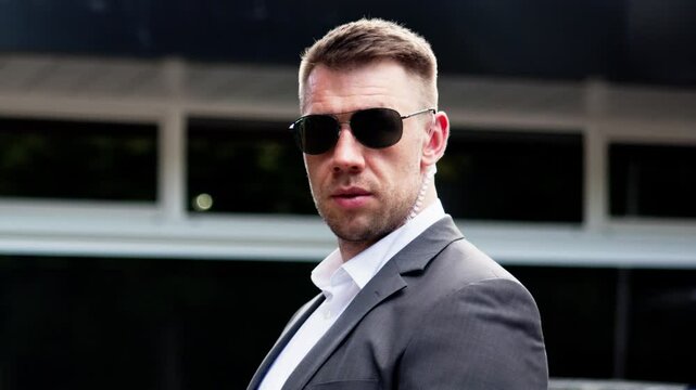 Confident security guard wearing sunglasses stands watch at entrance, ready