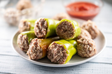 Stuffed green peppers on a plate ready for cooking or baking