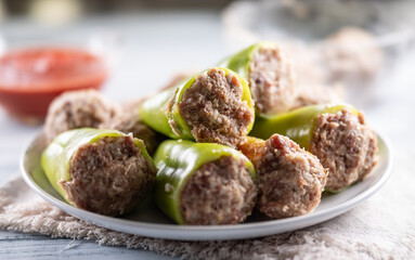Stuffed green peppers on a plate ready for cooking or baking.