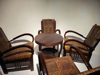 Round table with 4 chairs, crafted from dark brown wood, classic ambiance amidst a white room.