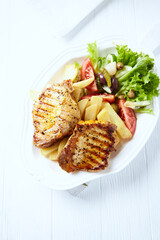 Grilled Steaks with french fries and fresh salad. Bright wooden background.	