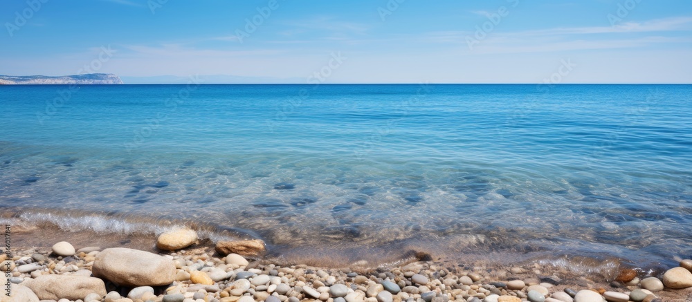 Poster copy space image showcasing rocks and sand in the ocean under a clear blue sky with a water backdrop
