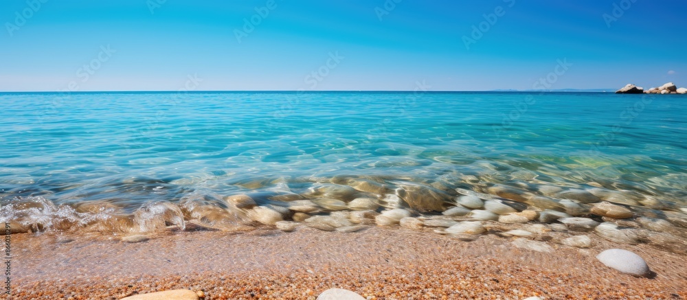 Poster copy space image showcasing rocks and sand in the ocean under a clear blue sky with a water backdrop