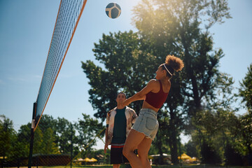 Below view of woman playing beach volleyball with friends.