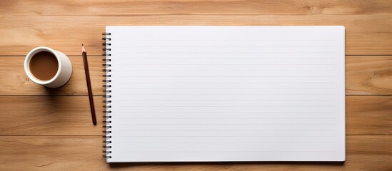 Top view of a wooden office desk with pencils and a blank notebook page in the center for text input, creating a copy space image.