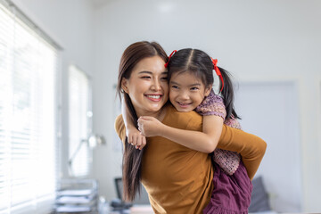 cheerful asian toddler daughter hugging happy mother Good time at home.