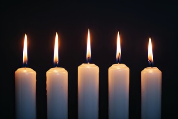 Five burning white candles on black background. Concept of memory, mourning, grief, loss, hope, or faith.
