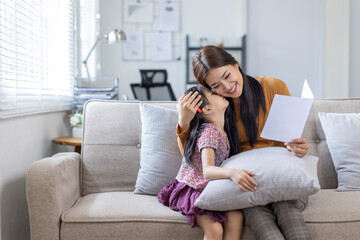 Fototapeta premium Asian business lady working on computer while her daughter hugging her