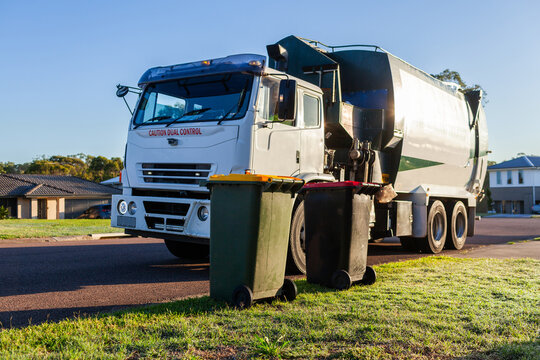 Recycling truck picking up bin from suburban roadside