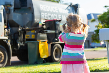 Kid watching noisy garbage truck emptying bin with hands over ears