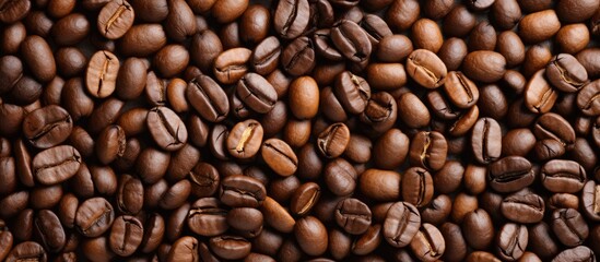 Fototapeta premium A top view of beige coffee grains on a textured background with copy space. Macro shot of roasted brown beans in natural sunlight on a table, perfect for cappuccino.