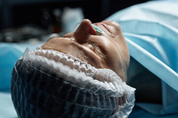 Close up of mature female patient lying on operating table preparing for surgery copy space