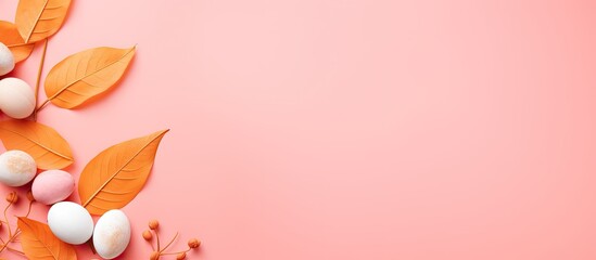 Fototapeta premium Easter-themed flat lay with an orange leaf and painted eggs on a pink background, offering copy space image.