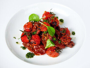 Gourmet roasted cherry tomatoes garnished with herbs on a white plate