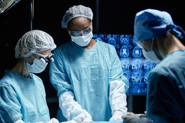 Waist up portrait of surgical team performing surgery on unrecognizable patient in operating room...