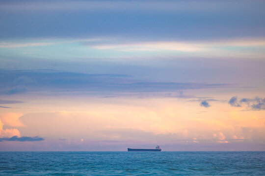 Cargo ship lined up at sea en route to Newcastle Harbour under a vibrant sunset sky