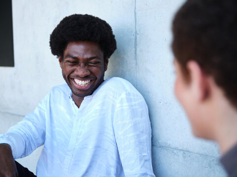 Man and woman sitting against a concrete wall having a conversation