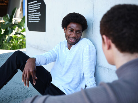 Man and woman sitting against a concrete wall having a conversation