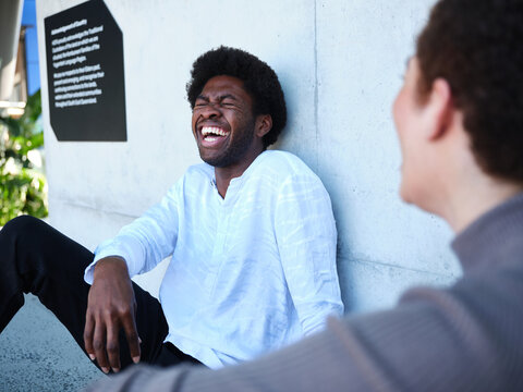 Man and woman sitting against a concrete wall having a conversation