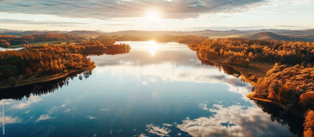 Poster a serene aerial photograph capturing the autumn sun reflecting on a vast lake with ample space for t