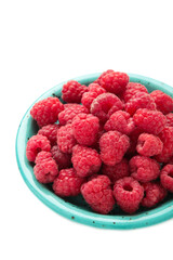 Raspberries in blue bowl isolated on white background
