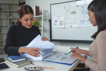 Confident businesswoman working with laptop in office Female office worker uses a calculator to perform financial calculations. Search for piles of documents, accounting, online marketing.