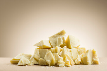 Pile of white chocolate flakes on cream colored background.