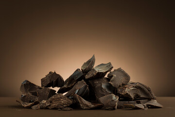 Pile of dark chocolate flakes on brown background.